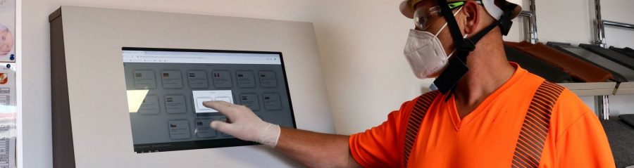 Production Operative signing-in via touch-screen portal during Covid-19 operations.