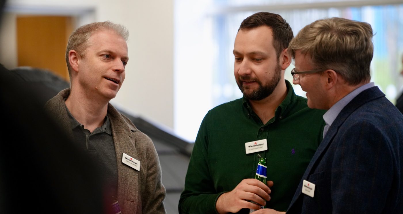 Three men stood talking at an event
