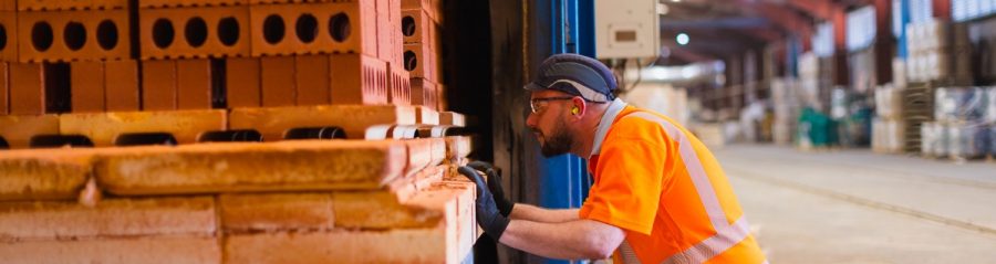 Man in safety PPE inspecting fired bricks at factory site