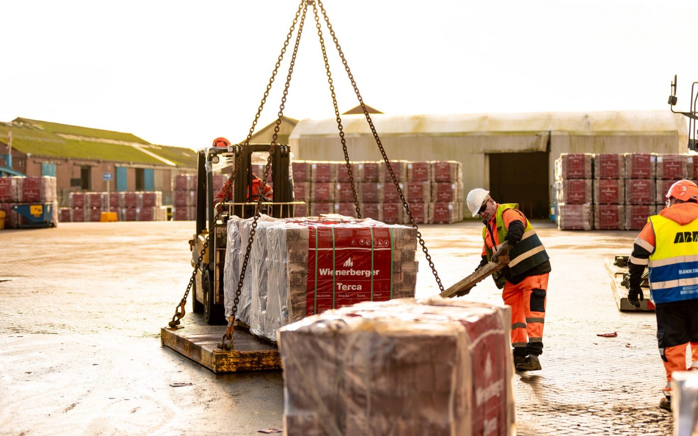 Man loading pallet of bricks onto crane for transport