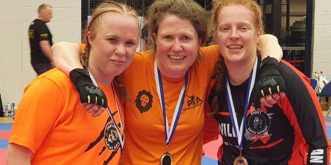 Three women with medals round their necks for taekwondo