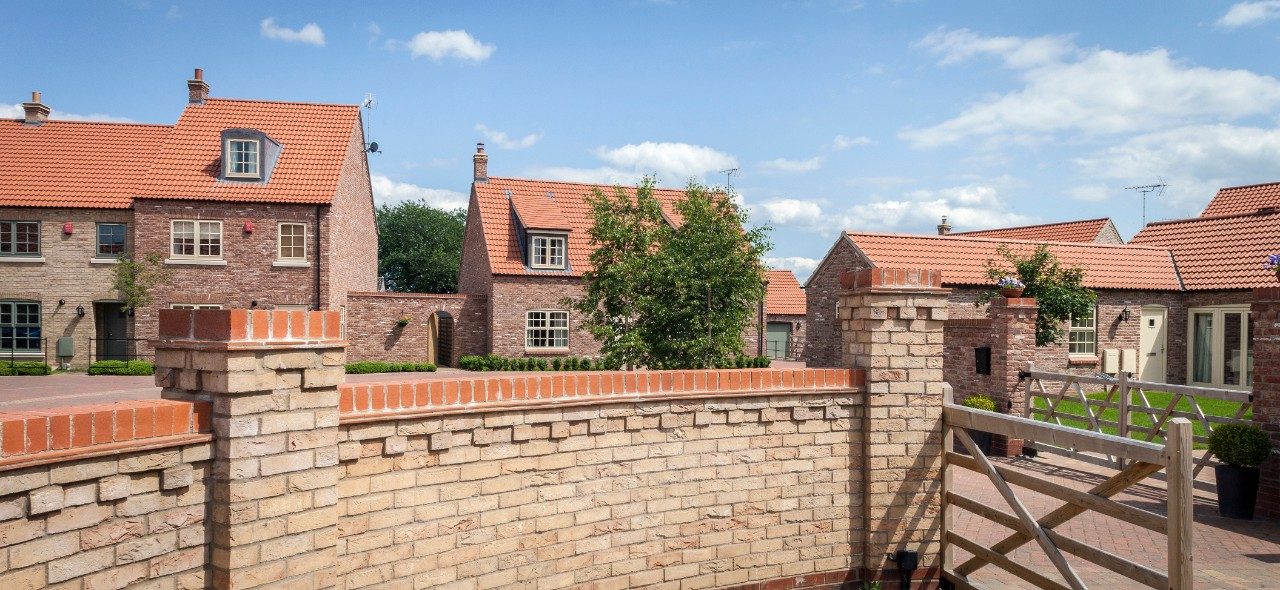 Brick wall and gate leading to modern housing development
