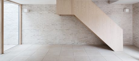Minimalist interior design with wooden staircase and white brick wall